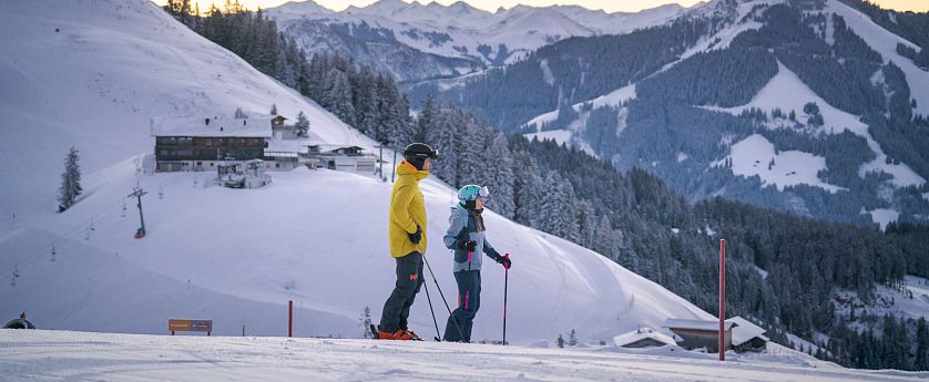 Zwei Skifahrer stehen auf Piste bei Kleiner Salve mit Blick auf Brixental in SkiWelt Itter