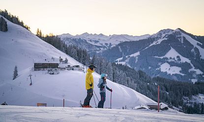 Skifahrer stehen am Hang und betrachten die Berge um sich herum.