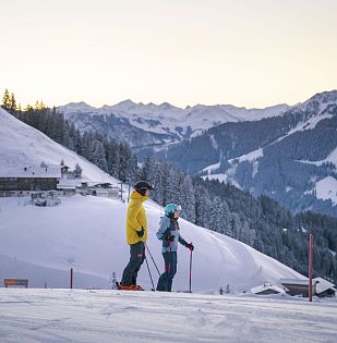 Skifahrer stehen am Hang und betrachten die Berge um sich herum.