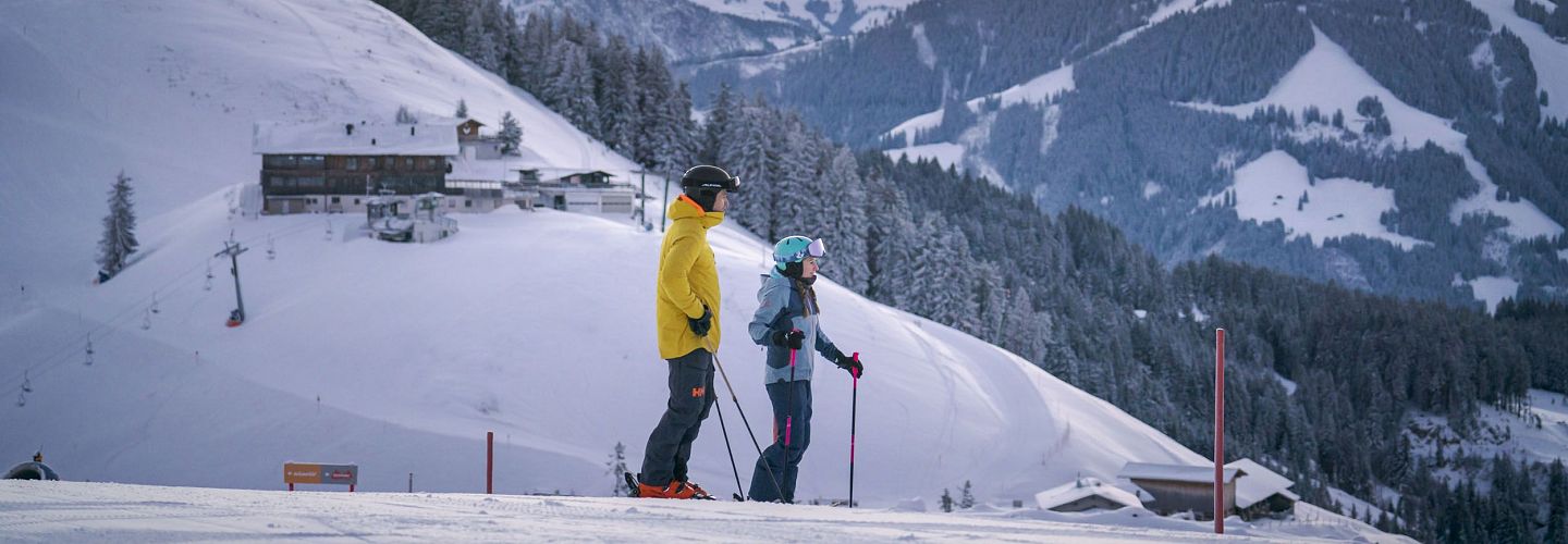 Skifahrer stehen am Hang und betrachten die Berge um sich herum.