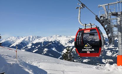 Uitzicht op besneeuwde Alpenbergen vanuit een rode kabelbaan, zonnige en heldere hemel.