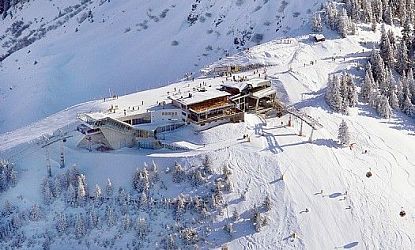 Besneeuwd bergstation met skiliften en omringde bomen in een winterlandschap, ideaal voor wintersport.