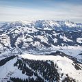 Luchtfoto van een bergachtig gebied bedekt met sneeuw en een dorp in de vallei, omringd door besneeuwde bomen en bergen.